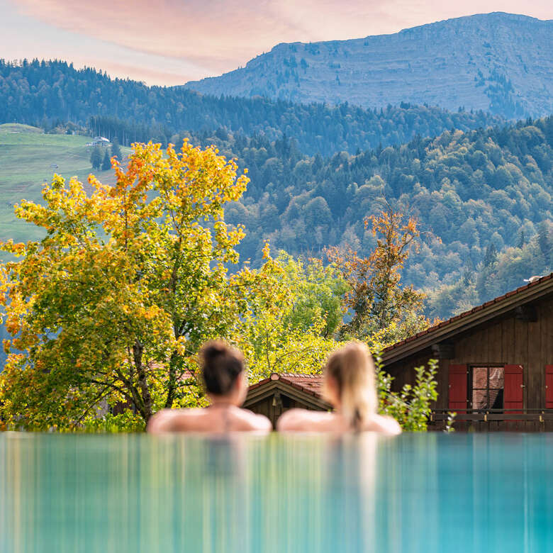 Baden mit Blick auf den Hochgrat im Outdoorpool eines Wellnesshotels in Oberstaufen.