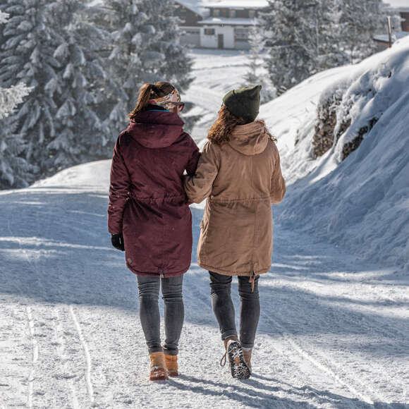 Zwei Frauen laufen auf einem geräumten Winterweg.