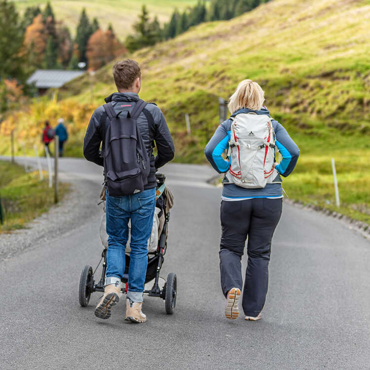 Paar wandert mit dem Kinderwagen in Oberstaufen