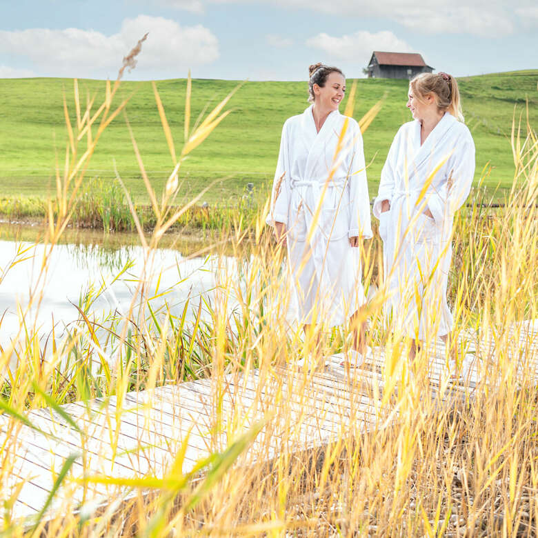 Auszeit im Bademantel am Naturbadesee eines Wellnesshotels inmitten der Allgäuer Natur.