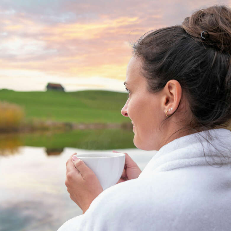 Frau genießt den Sonnenuntergang im Gesundheitsurlaub in Oberstaufen mit einer Tasse Tee