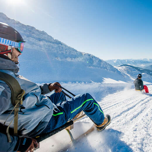 Zwei Rodler auf der Rodelbahn am Hochgrat an einem sonnigen Tag.