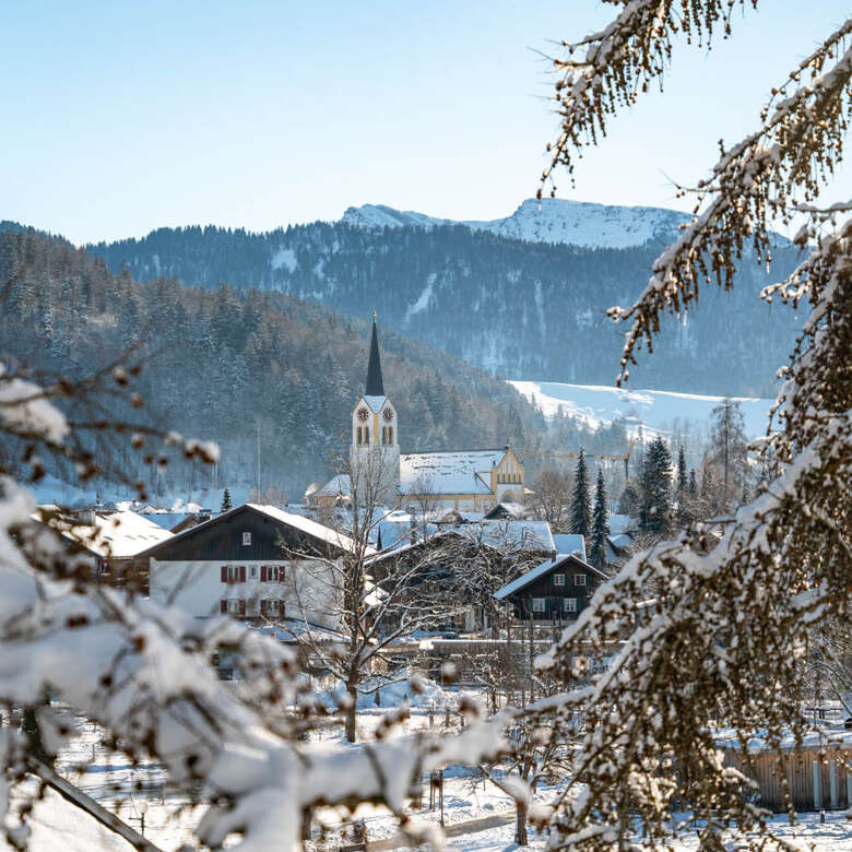 Winteransicht von Oberstaufen mit Kirche und Bergen