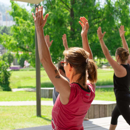 Gruppe macht Yogaübungen mit erhobenen Armen bei den Achtsamkeitstagen im Kurpark von Oberstaufen im Allgäu