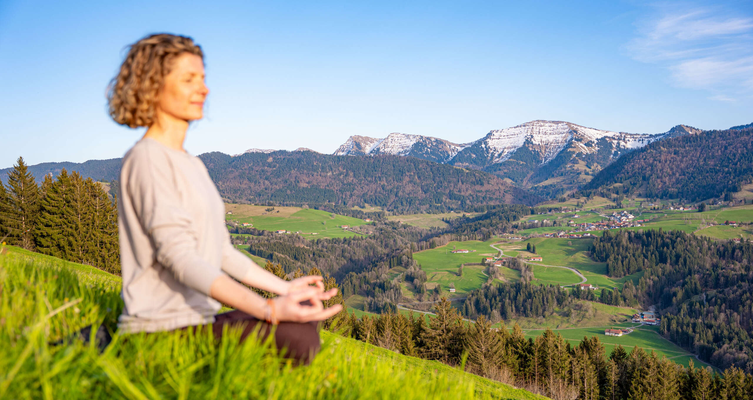 Frau im Loutus-Sitz am Paradies in Oberstaufen mit Weitblick auf die Berge