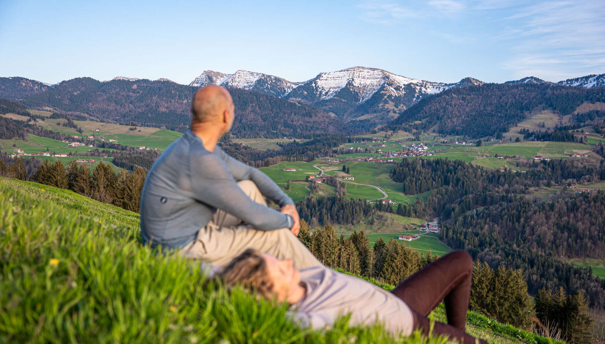 Pausen in der Natur erleben Mann und Frau entspannen in der Wiese am Paradies mit Weitblick auf den Hochgrat und die Berge