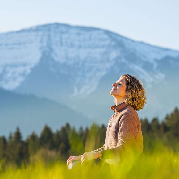 Frau im Lotus-Sitz in der Wiesen mit Hochgratpanorama