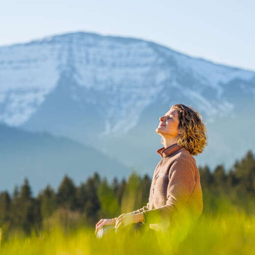 Frau im Lotus-Sitz in der Wiesen mit Hochgratpanorama