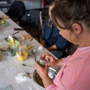 Frau stellt im Workshop beim Oberstaufener Weitblick Naturkosmetik in einem kleinen Glas her