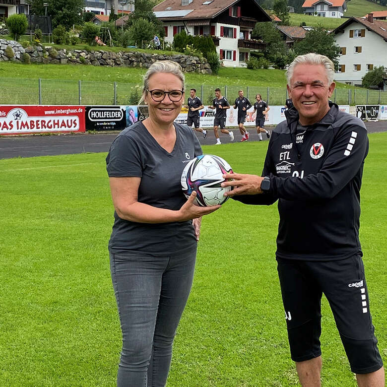 Trainer der Prodifußballer Mannschaft Viktoria Köln und Tourismusdirektorin Constanze Höfinghoff . Beide halten einen Fußball zusammen in der Hand.
