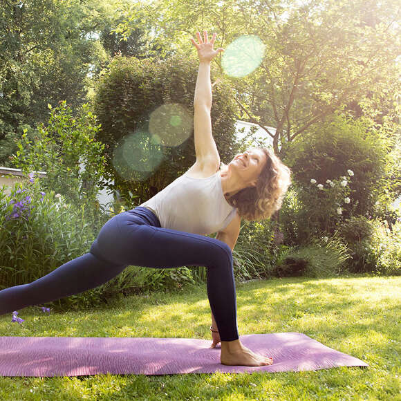 Yoga Lehrerin praktiziert auf ihrer Matte in der Allgäuer Natur