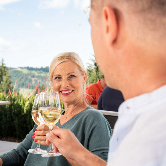 Paar stoßt mit Weißwein in einem Restaurant an.