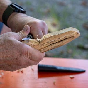 Workshop Buttermesser schnitzen Huimatwochen 2026 Draußen wird an einem Stück Holz geschnitzt bei den Huimatwochen