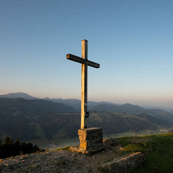 Gipfelkreuz der Salmaser Höhe im Morgenlicht der aufgehenden Sonne im Allgäu