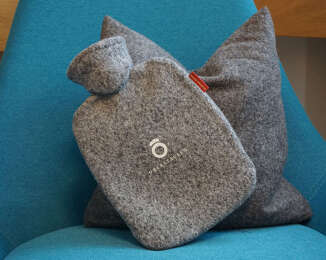 Die graue Oberstaufen Wärmfläsche liegt auf einem Sessel.