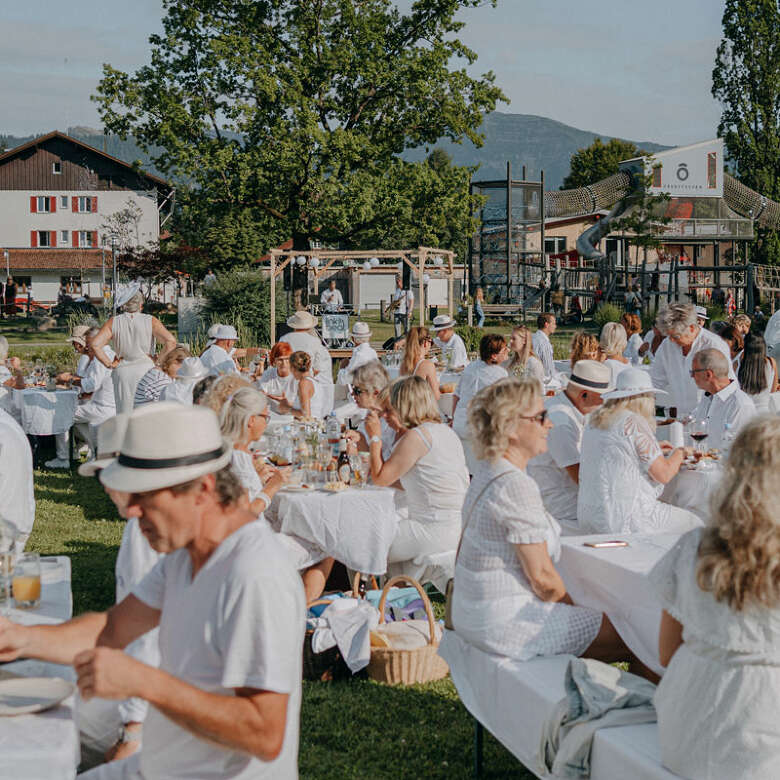 Menschen picknicken in weißen Klamotten im Oberstaufen Park