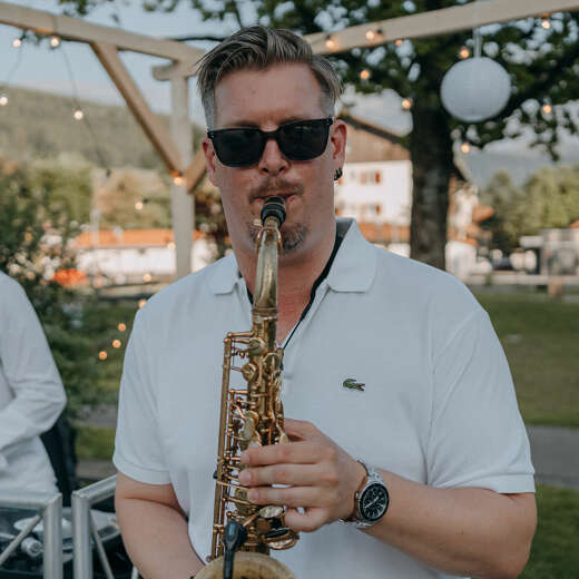 Musiker spielt Saxophon beim Picknick in Weiß in Oberstaufen