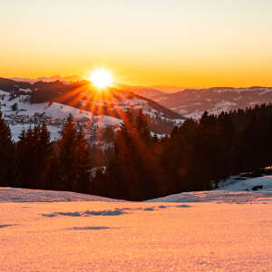Blick vom Hündle Richtung Steibis auf einen Sonnenuntergang im Winter.