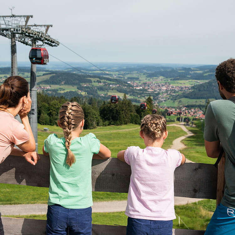Familie genießt den Ausblick von der Bergstation der Imbergbahn über die grüne Natur von Oberstaufen