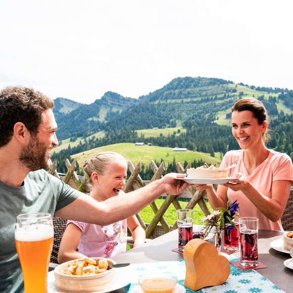 Familie beim Essen auf einer Hütte im Imberggebiet mit Bergpanorama