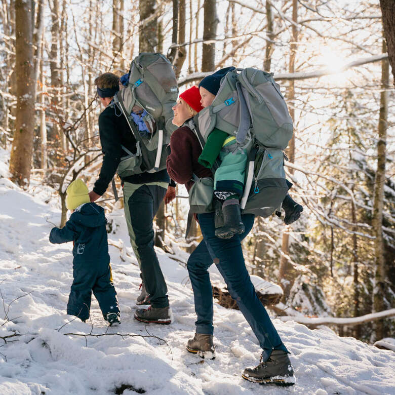 Familie wandert mit Kindern durch den verschneiten Wald am Staufen