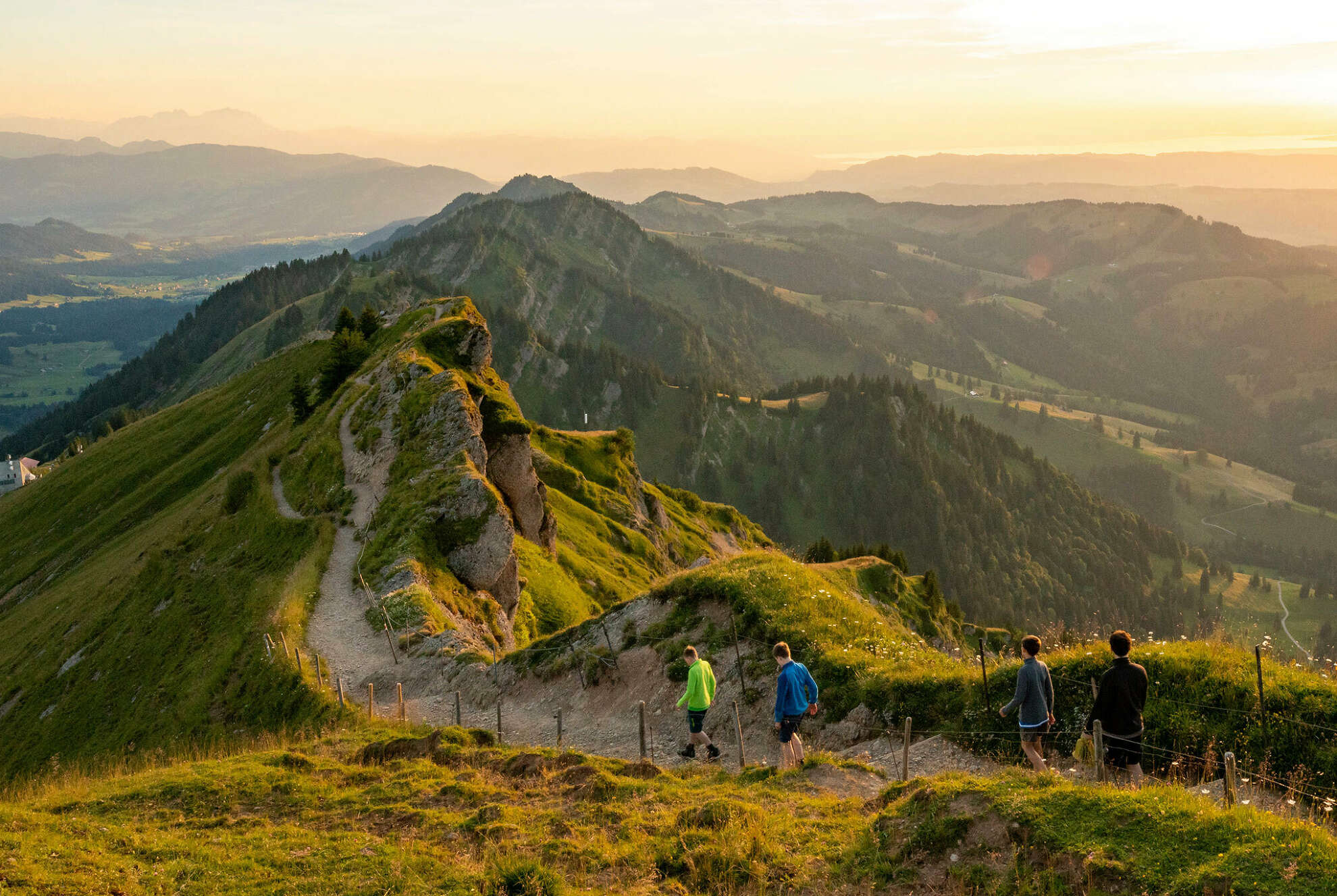 Familie auf dem Gratwanderweg des Hochgrats während des Sonnenuntergang mit Bergpanorama.