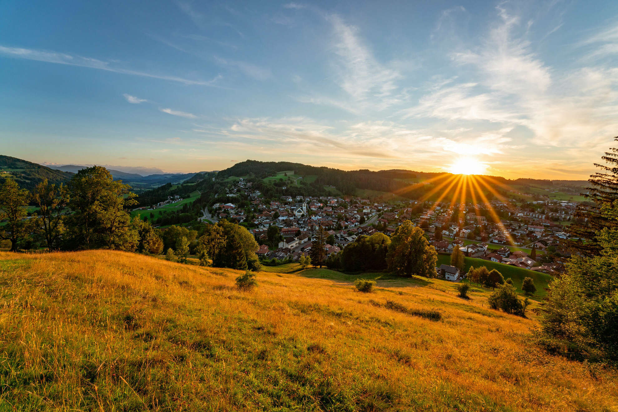 Die Sonne geht über dem Ort Oberstaufen im Allgäu unter