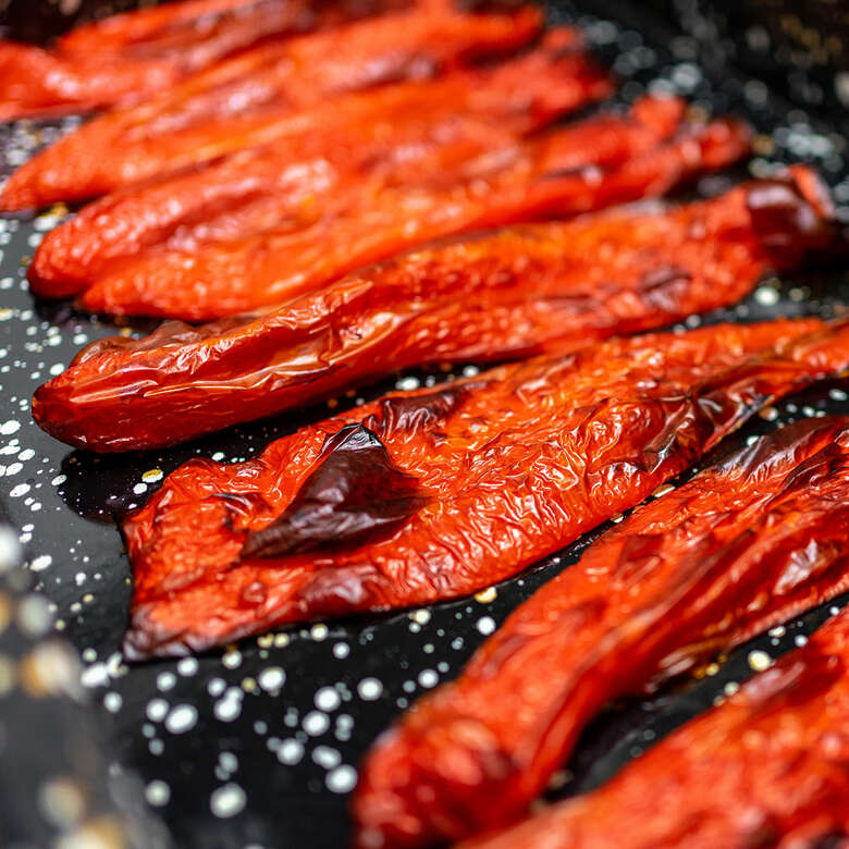 Rote Paprika wird im Backofen gebacken bis sie schwarze Stellen hat.