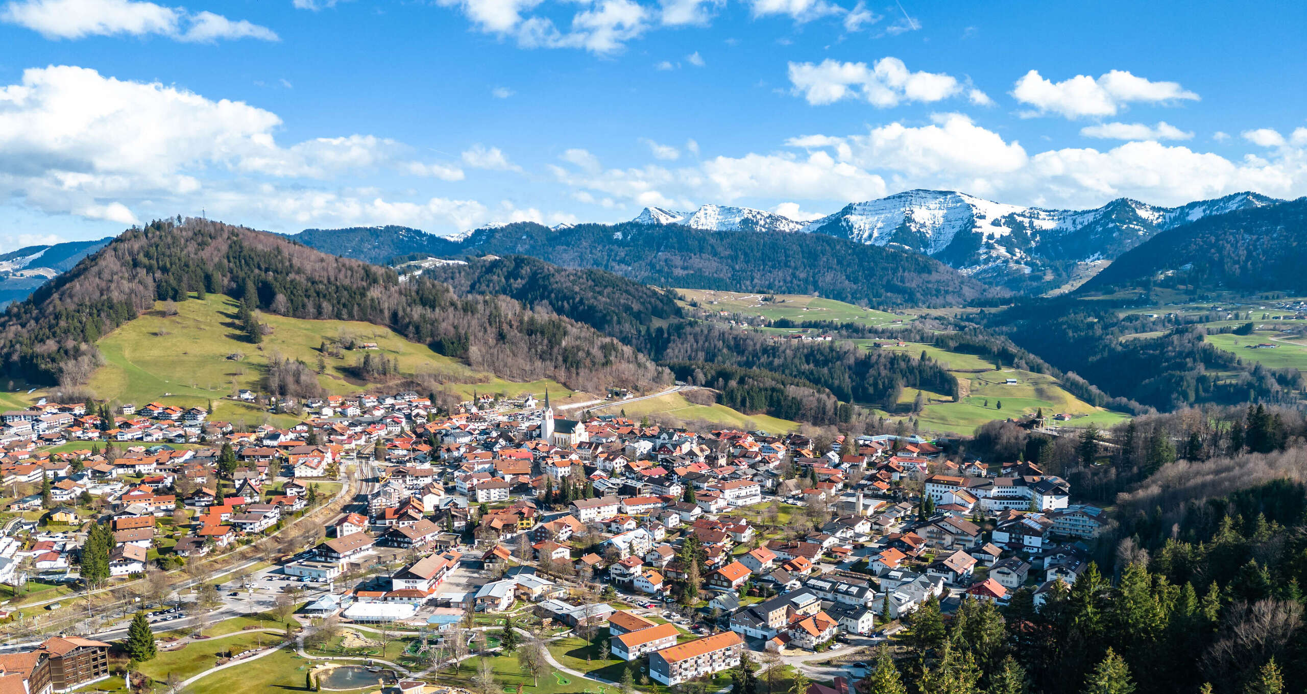 Ortspanorama von Oberstaufen mit dem schneebedeckten Bergen im Frühling
