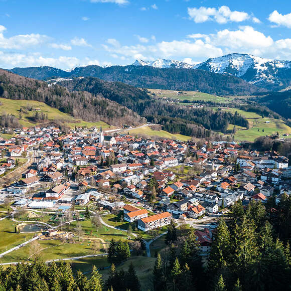 Ortspanorama von Oberstaufen mit dem schneebedeckten Bergen im Frühling
