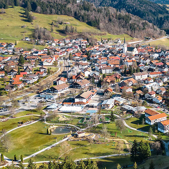 Ortspanorama von Oberstaufen mit dem schneebedeckten Bergen im Frühling