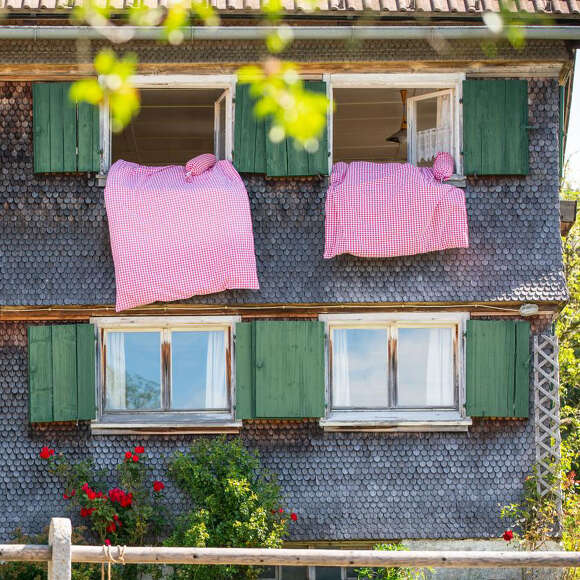 Traditionelles Allgäuer Haus mit Bettzeug an den Fenstern