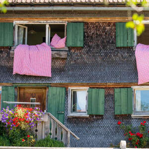Traditionelles Allgäuer Haus mit Bettzeug an den Fenstern