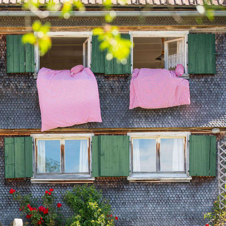 Gelebte Gastfreundschaft Traditionelles Allgäuer Haus mit Bettzeug an den Fenstern