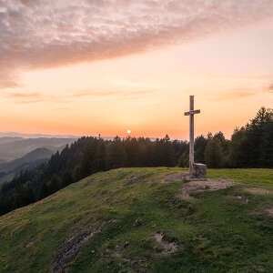 Gipfelkreuz der Salmaser Höhe mit Weitblick auf die Natur von Oberstaufen im Sonnenuntergang