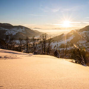 Blick Richtung Weißachtal bei untergehender Sonne im Winter mit verschneiter Landschaft.