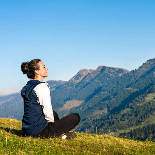 Frau sitzt entspannt auf dem Imberg und genießt das Bergpanorama der Nagelfluhkette