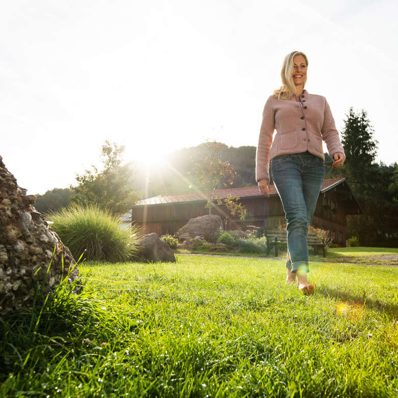 Frau läuft über Wiese an einem Sommermorgen.