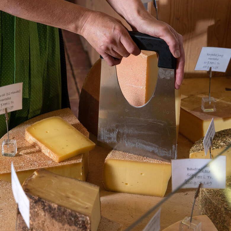 Allgäuer Bergkäse Allgäuer Bergkäse wird im Verkauf geteilt.