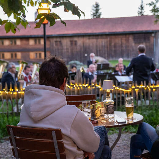 Konzert Musikkapelle Aach beim Wirthaus Strumpar Zwei Damen hören bei abendliche Stimmung dem Konzertauftritt der Musikkapelle während der Huimatwochen zu