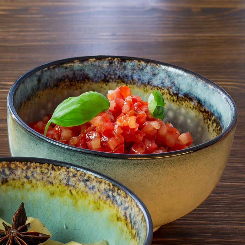 Die frischen Zutaten der leckeren Tomatensalsa liegen in einer Schale.