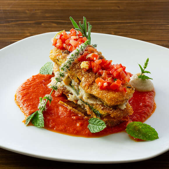 Zucchini-Lasagne angerichtet auf einem Teller mit Tomatensoße und Tomatensalsa