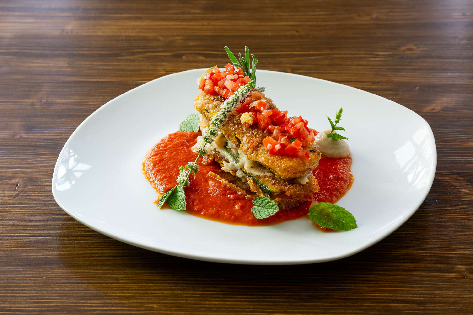 Auf einem Teller ist die Gemüselasagne mit Zucchini und Tomatensalsa angerichtet.