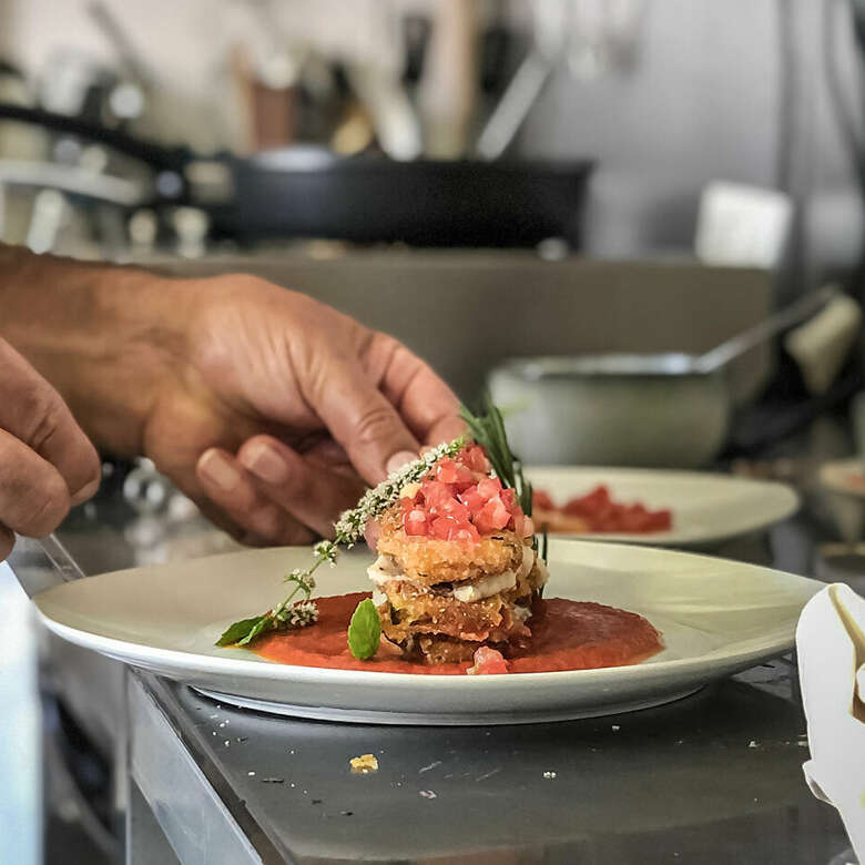 Anrichten der Zucchini-Lasagne mit Tomatensoße auf einem Teller