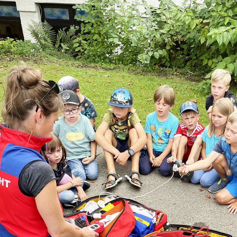 Frau von der Bergwacht Oberstaufen erklärt Kindern den Erstehilfekoffer