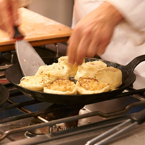 Koch wendet Allgäuer Krautkrapfen in der Pfanne