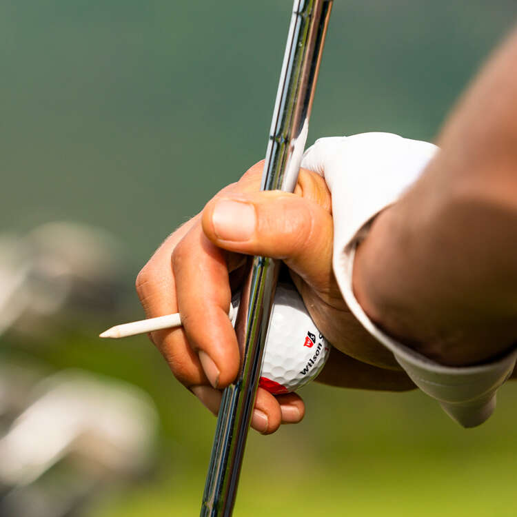 Spieler hält Golfschläger und -ball in der Hand