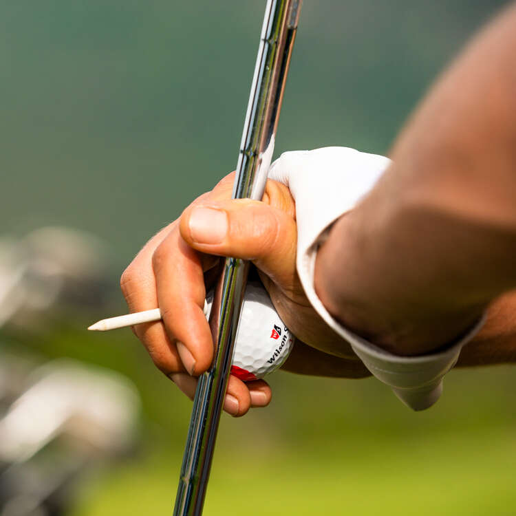 Golfer hält Golfschläger und Golfball in der Hand