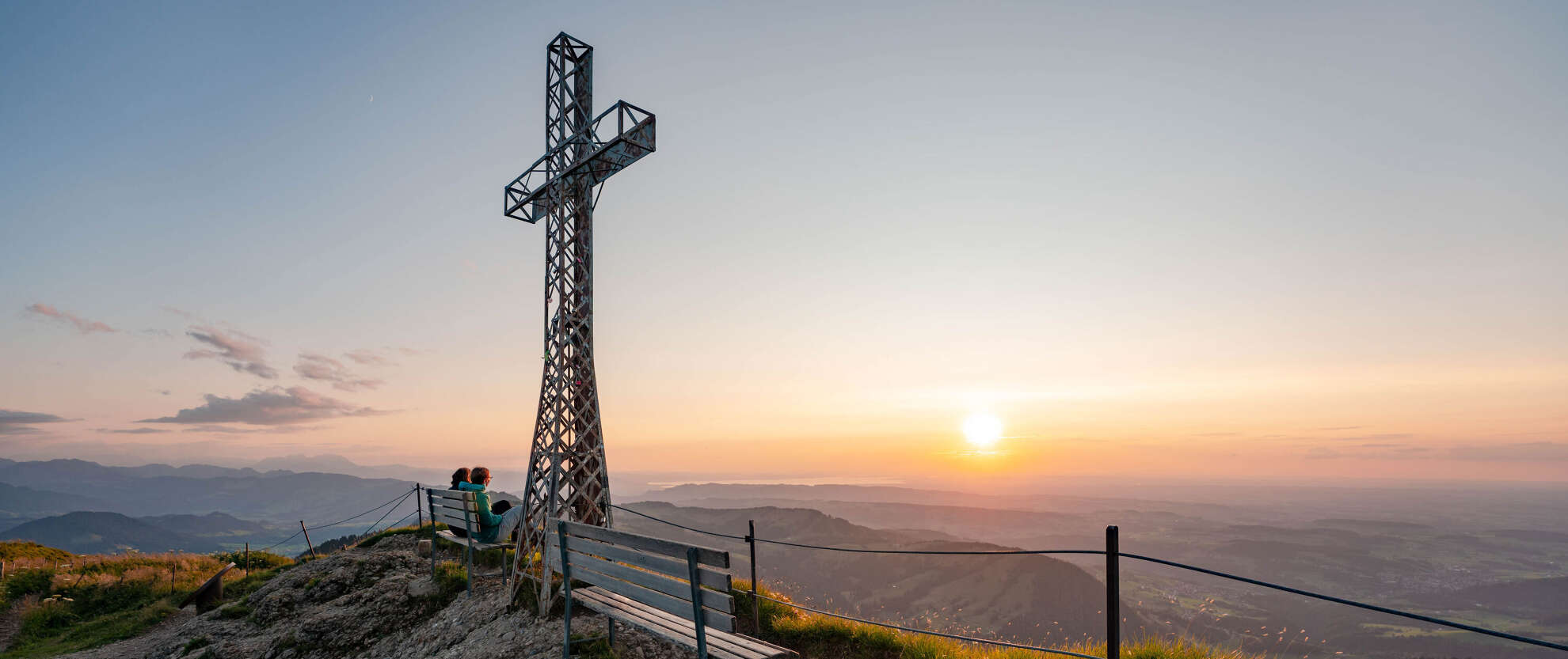 Hochgrat Gipfelkreuz mit Ausblick im Sonnenuntergang Auf dem Hochgrat-Gipfel mit Ausblick auf die Berge um Oberstaufen in der untergehenden Sonne