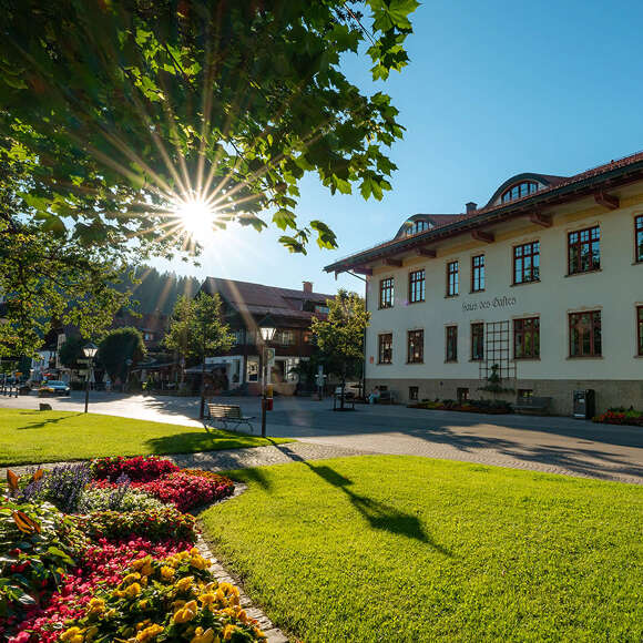 Haus des Gastes in Oberstaufen im Sommer umgeben von blühenden Beeten